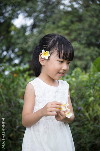 Asian Chinese little girl holding flowers in outdoor garden