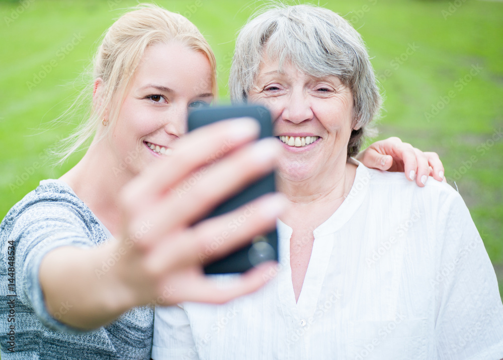 Young and old woman taking a picture with smart phone