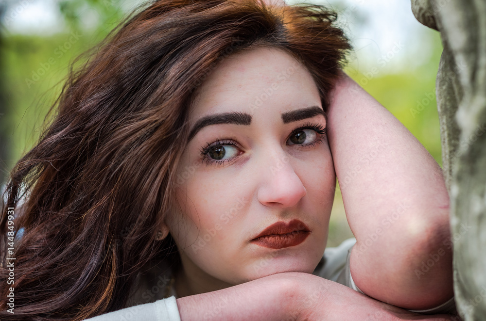 Portrait of a sad young beautiful girl with long dark hair