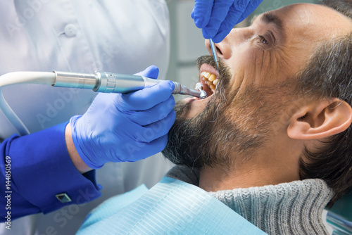 Fototapeta Naklejka Na Ścianę i Meble -  Dentist cleaning teeth. Hands of stomatologist with tools. Dental health services.