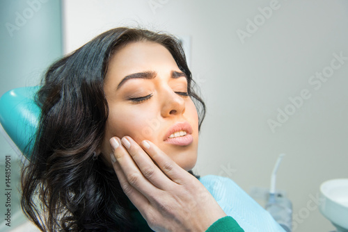 Young woman having toothache. Sad lady at the dentist. Gum disease symptom.