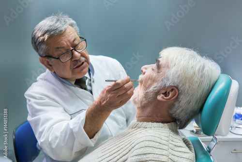 Elderly man at the dentist. Stomatologist is examining patient. High experience in medicine.