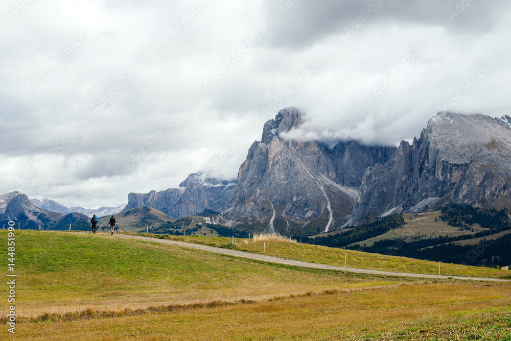 Two friends with a backpack on route to the mountains in the Dolomite, Italy