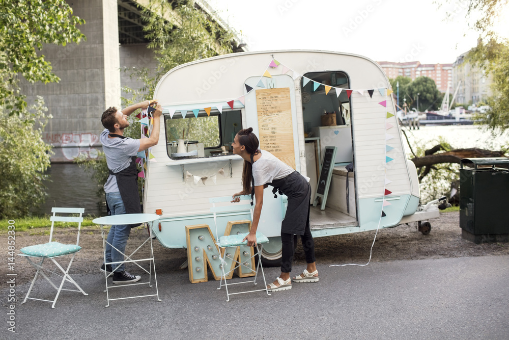 Male and female owners working outside food truck on street Male and female owners working outside food truck on street