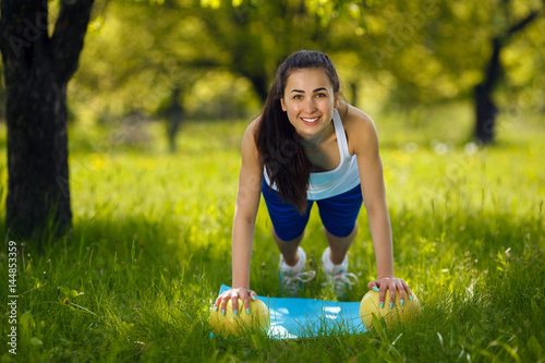 Young girl working out outdoors. Beautiful woman doing pilates, yoga and fitness exercices on nature. photo