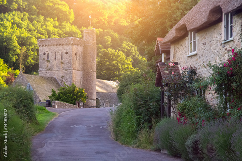 The road to the village of Branscombe. The old typical two-story Devonian house with a thatched roof. St Winfred's church. Devon. UK