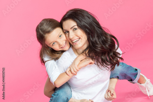 Happy beautiful mother and daughter hugging and smiling at camera