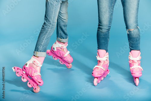 Φωτογραφία low section of mother and daughter in roller skates in studio on blue