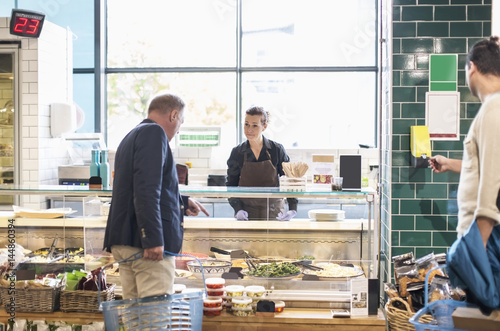 Mature man buying groceries from saleswoman in supermarket
