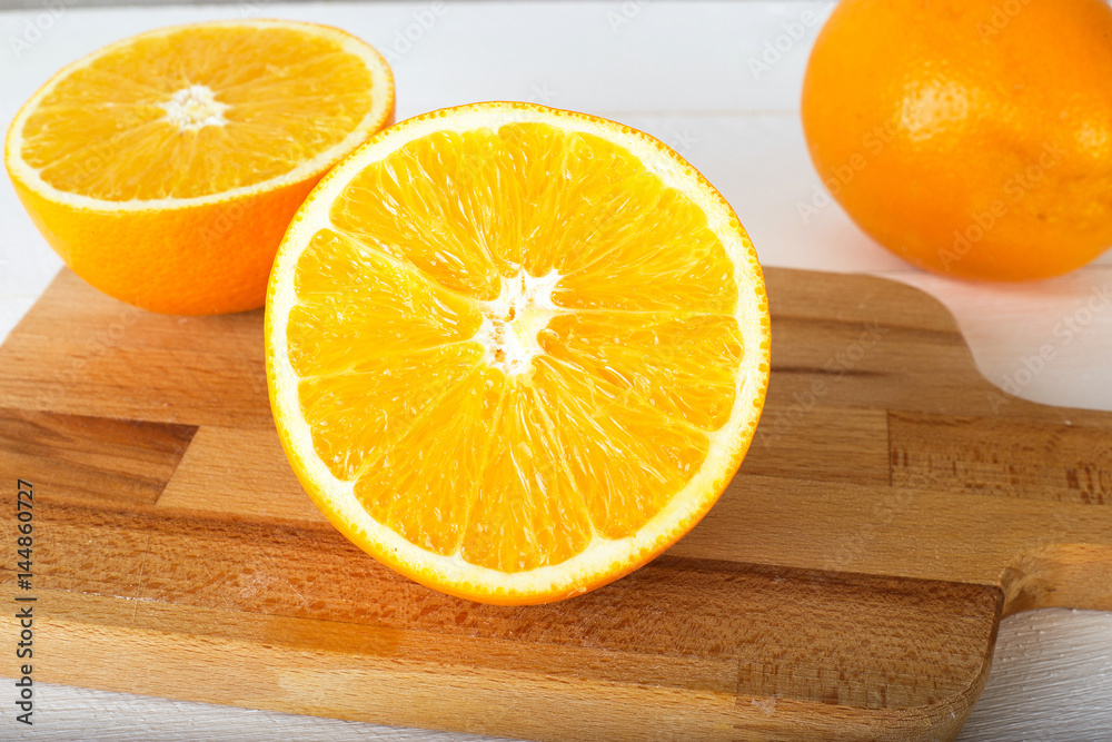 Fresh oranges,cutting board and juicer on white wooden background. Selective focus. Wellness setting. Health concept. Fresh oranges,cutting board and juicer on white wooden background. Selective focus. Wellness setting. Health concept.