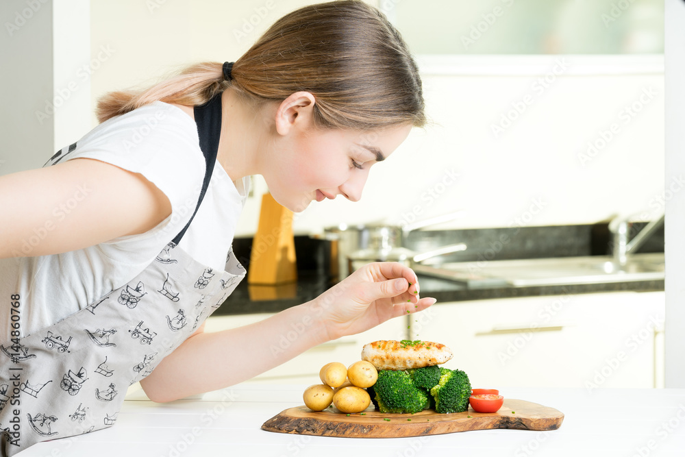 concentrated female chef garnishing food in the kitchen