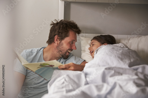 Father Reading Story To Daughter At Bedtime