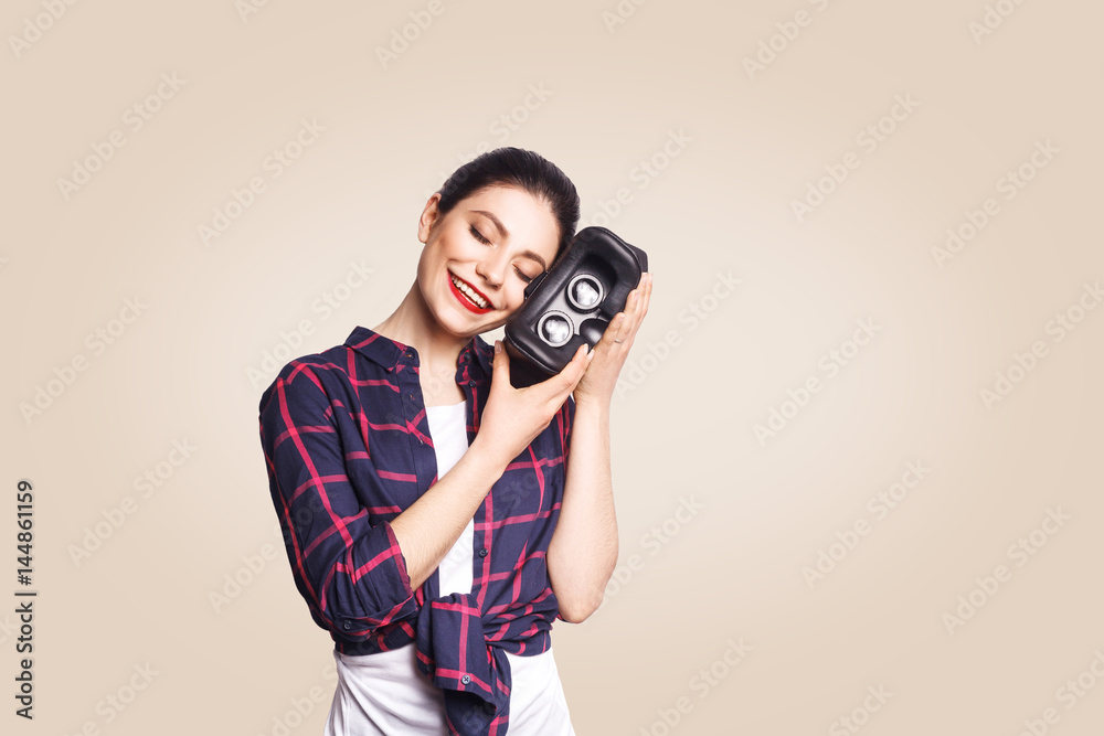 Obraz premium Young beautiful woman in casual style with virtual reality headset on beige background. studio shot. .