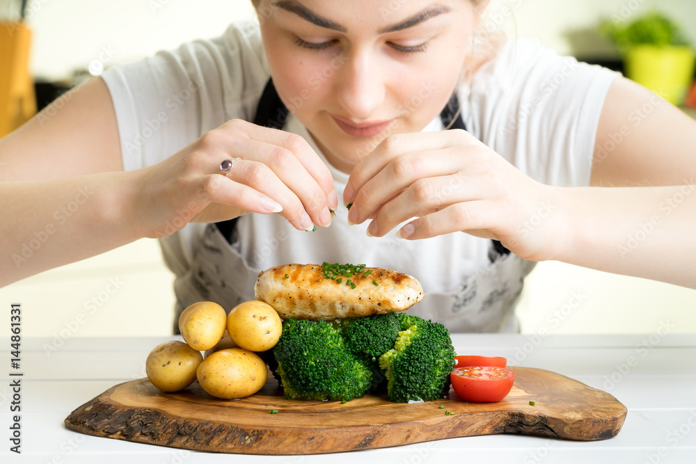 concentrated female chef garnishing food in the kitchen