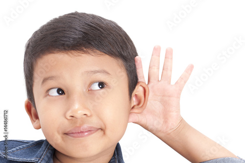 Little boy hearing something, hand to ear gesture on white background.