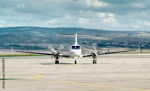 Small two propeller engine jet aircraft taxiing on the apron after landing, rotating propellers. Travel concept. 