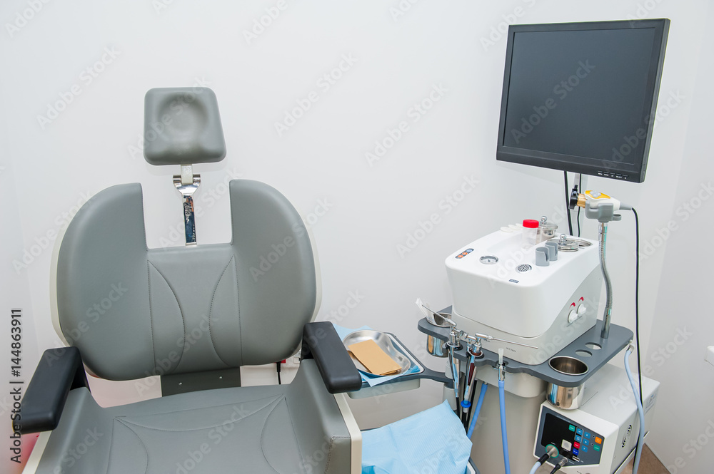 Fototapeta premium Interior of modern ENT clonic. Professional EVO ENT Medical Devices Workstation and chair in office. Ear Nose and Throat Medical equipment. Washing syringe. Selective focus