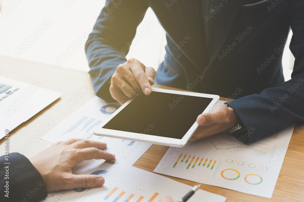 two young businessmen using touchpad and analysis business chart document at meeting two young businessmen using touchpad and analysis business chart document at meeting