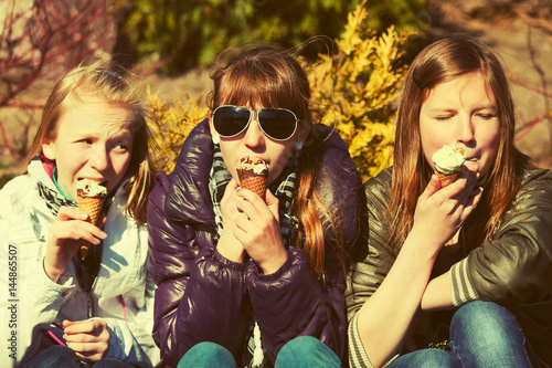 Happy teen girls eating an ice cream outdoor
