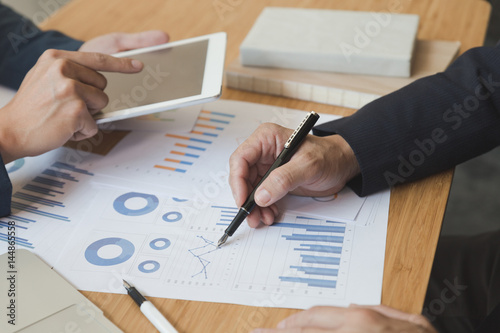 two young businessmen using touchpad and analysis business chart document at meeting