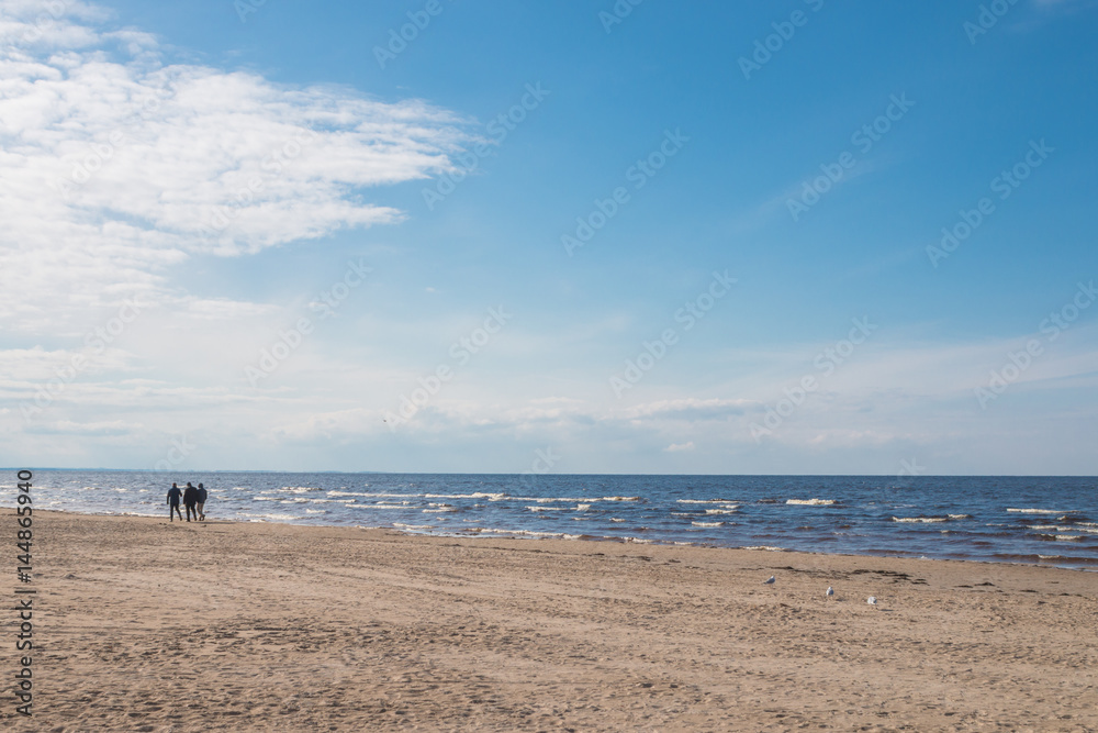 Jurmala, Latvia - April 16, 2017: The silhouettes of people enjoying romantic walking on sandy beach of the Baltic Sea