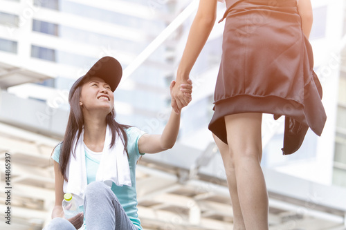 Asian woman giving helping hands for accident wonan during running photo