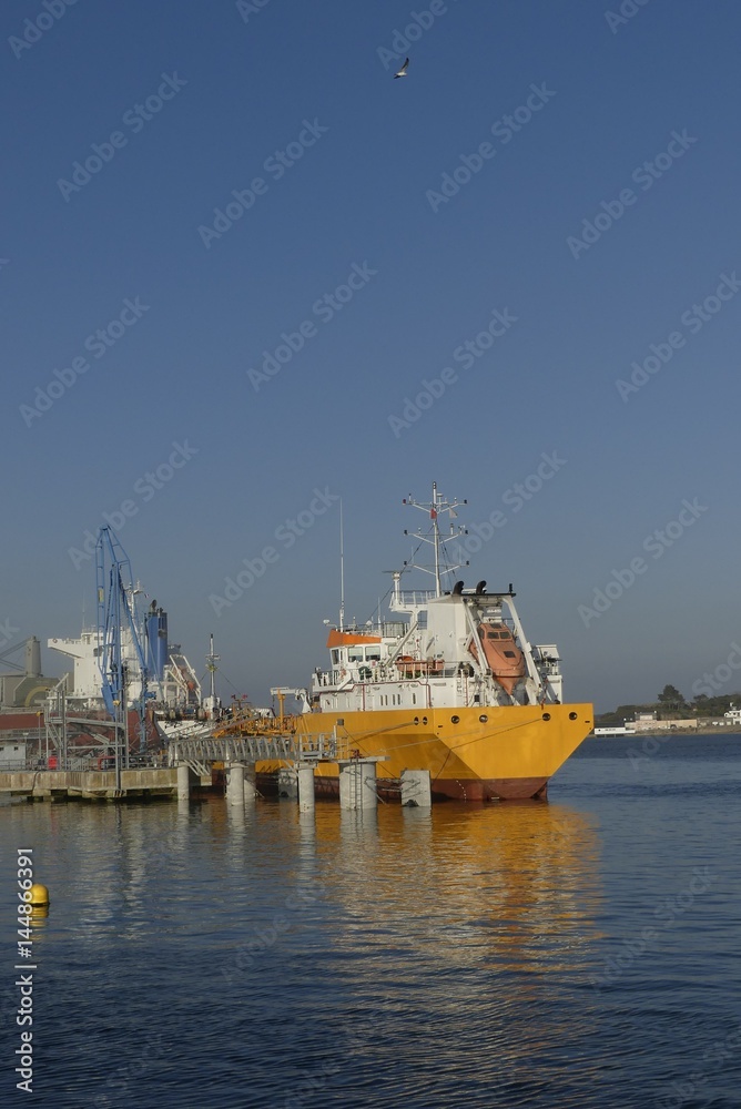 Products Tanker discharging at the Oil Terminal of Lorient, France, with yellow hull and white funnel on a sunny day