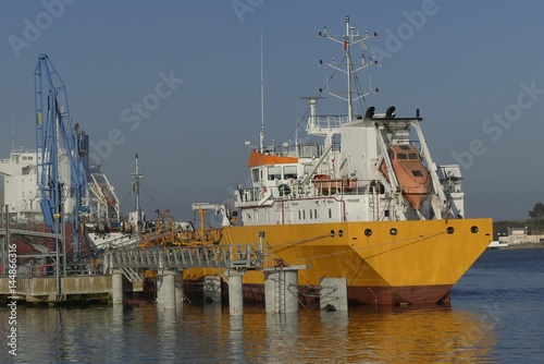 Products Tanker discharging at the Oil Terminal of Lorient, France, with yellow hull and white funnel on a sunny day