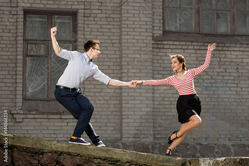 young couple dancing swing outside in front of old brick house