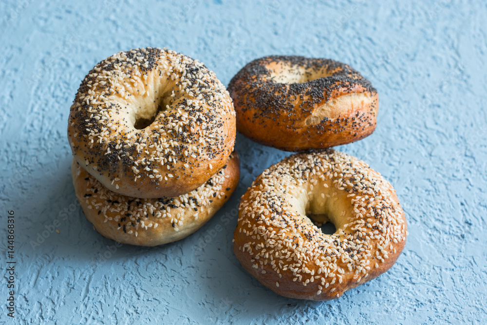 Homemade bagels with a variety of seeds on a blue background. Delicious breakfast or snack, tasty pastries