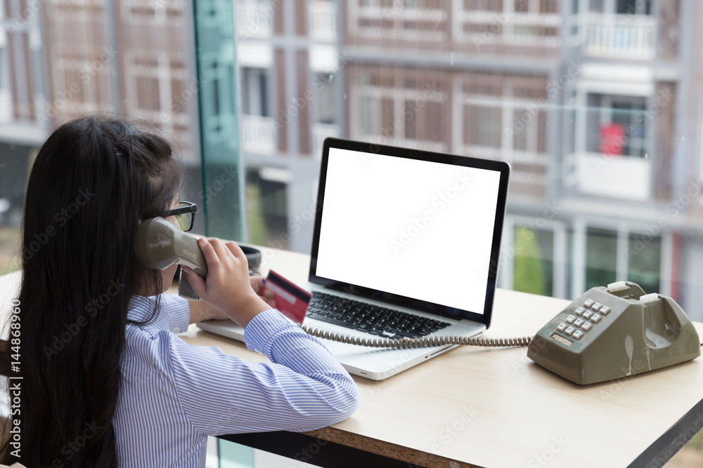 young asian girl holding credit card, making call, using telephone, talking on phone and using laptop for internet online shopping young asian girl holding credit card, making call, using telephone, talking on phone and using laptop for internet online shopping