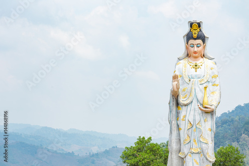 Quan Yin, the goddess of compassion and mercy, statue standing on the top of hill. photo