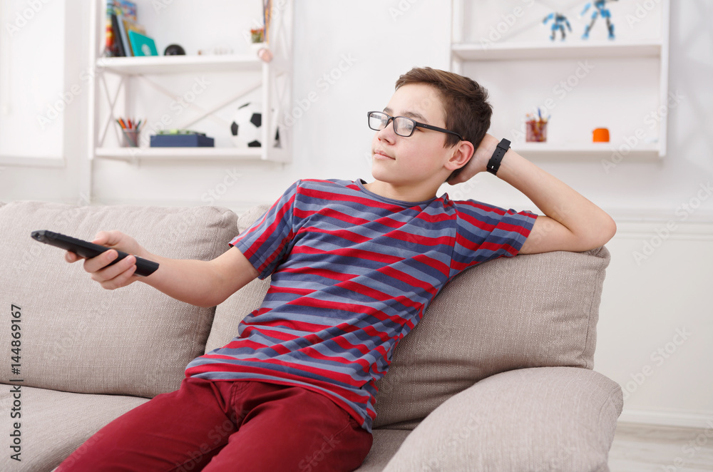 Teenager boy watching television, using TV remote