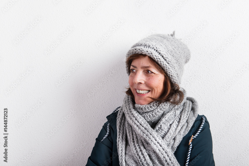 Senior woman in woolen scarf and hat, studio shot.
