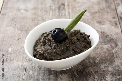 Black olive tapenade with anchovies, garlic and olive oil on wooden background

