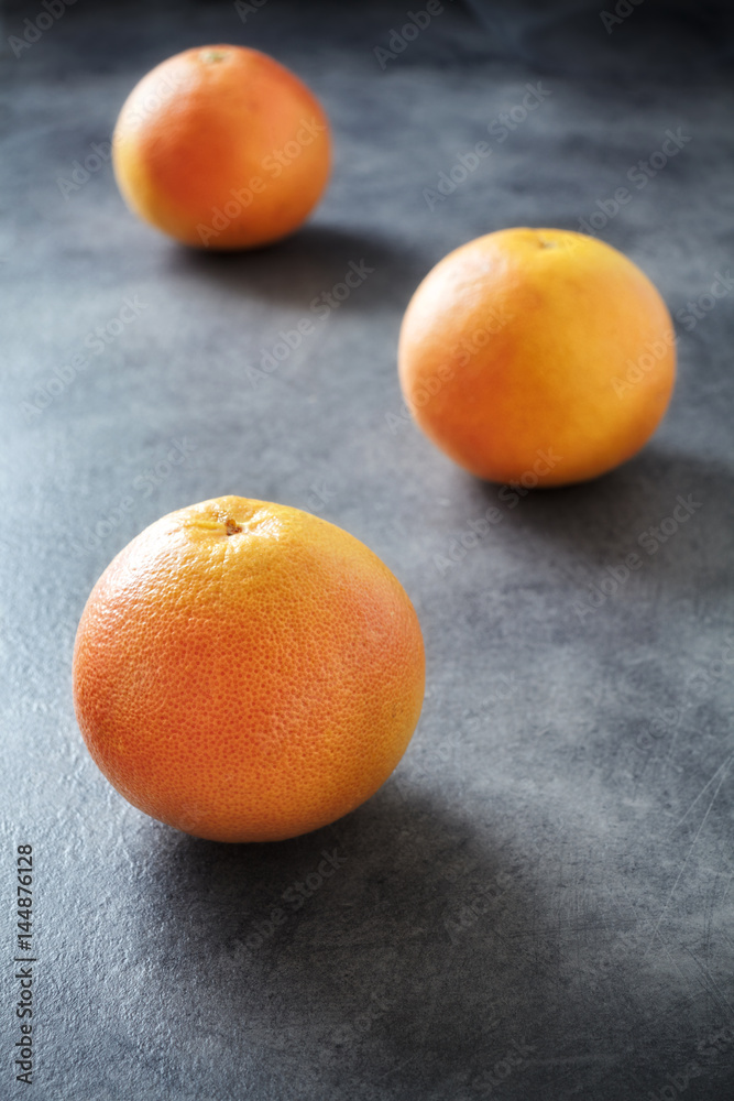 Three whole ripe grapefruits on dark background, selective focus. Three whole ripe grapefruits on dark background, selective focus.