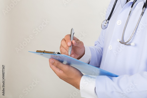 medical doctor man with a pen writing on clipboard. Medical care, insurance, prescription, paper work or career concept.