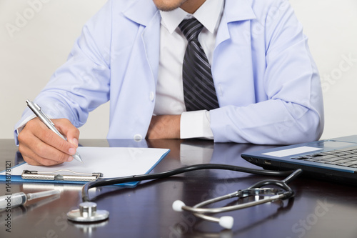 doctor writing RX prescription in medical office clinic on desk, stethoscope with clipboard