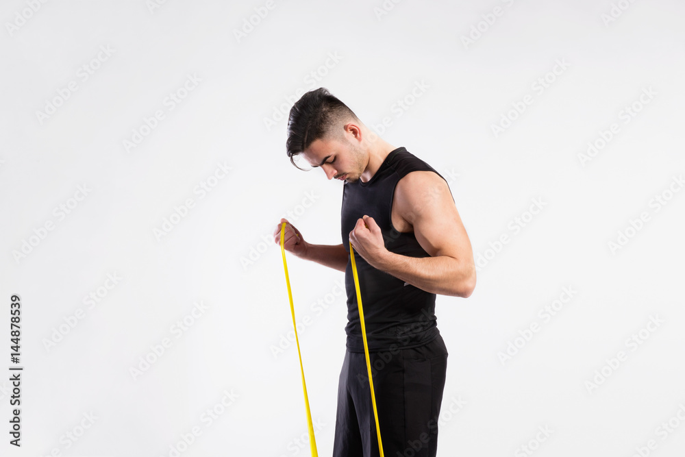 Handsome fitness man working out with rubber band, studio shot. Handsome fitness man working out with rubber band, studio shot.