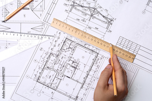 Man architect draws a plan, schedule, design, geometric shapes with a pencil and a wooden ruler. The figure is close to the transparent line of triangle