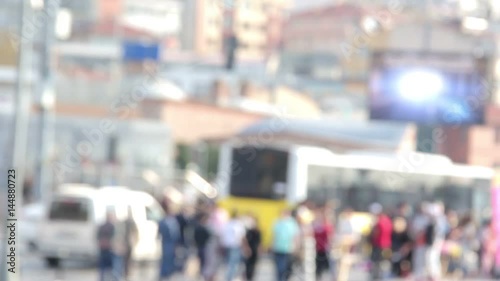 Telephoto shot with a backlit crowd of people on a wide sidewalk, walking