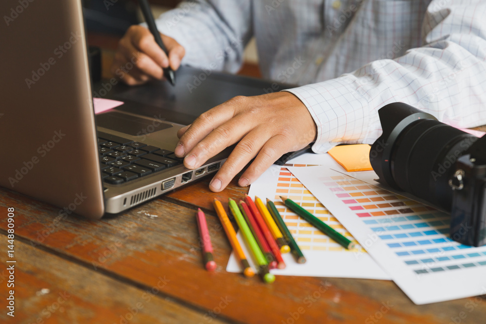 freelance graphic designer using digital tablet, computer, man working with color swatch catalog samples for selection - Creativity Editor Ideas Designer Concept