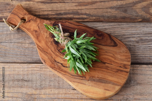 A bunch of fresh tarragon on a wooden cutting board