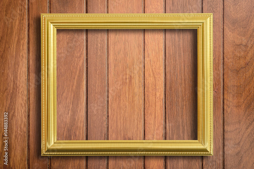 Gold picture frame on wood background.