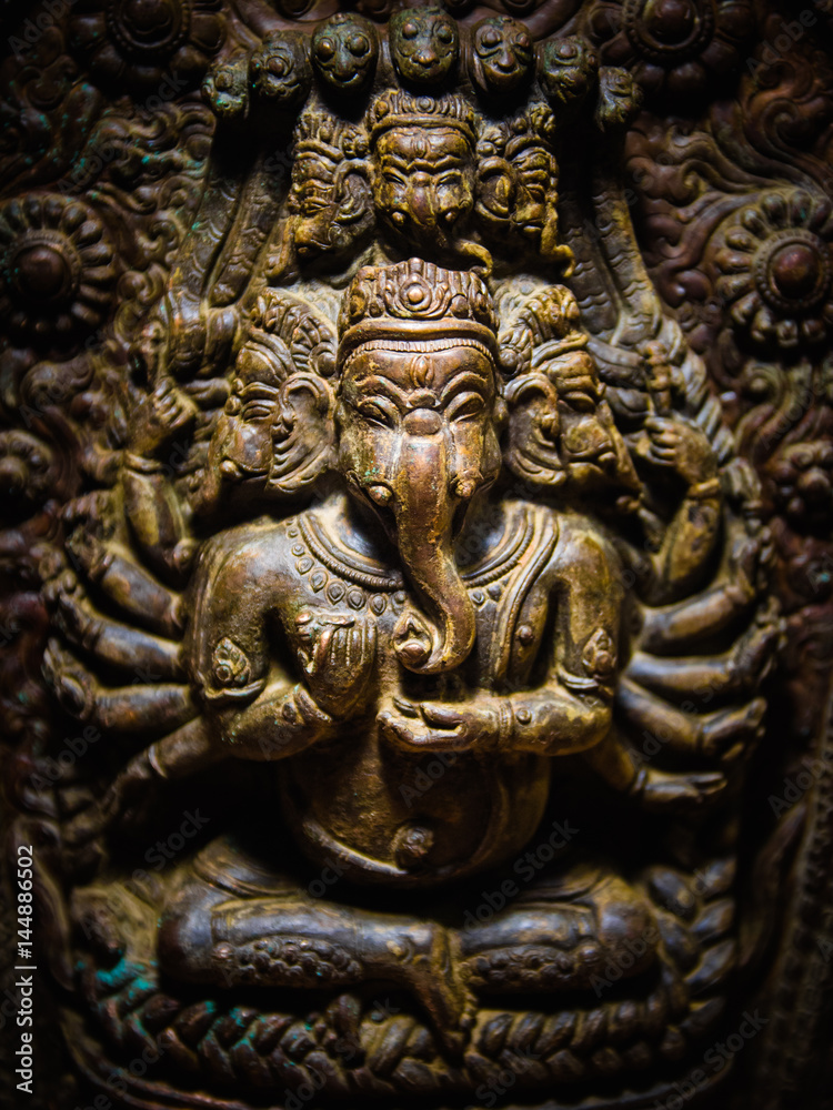 Intricately carved statue of the Hindu God Ganesha (elephant head) on display in the museum at Patan's Durbar Square, Nepal. Vignette and dramatic lighting.