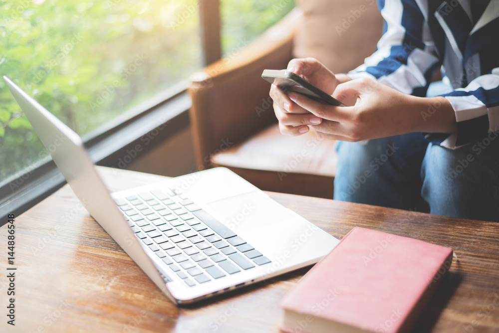 Woman sitting on leather sofa and using cell phone. Laptop, notebook on wooden table. Woman sitting on leather sofa and using cell phone. Laptop, notebook on wooden table.