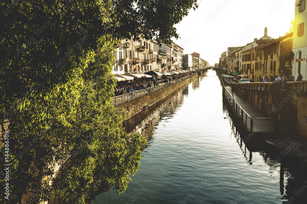 Fototapeta premium The Naviglio Grande canal waterway in Milan, Italy, at sunset. This district is famous for its restaurants, cafes, pubs and nightlife. 
