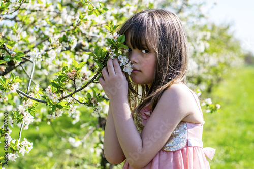 The little girl in a blossoming orchard