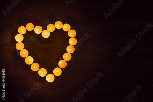  Save Download Preview A heart made of burning candles on a wooden background.