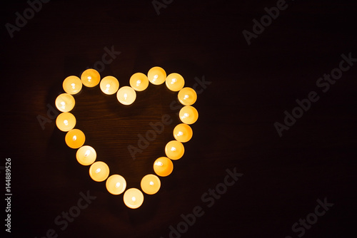  Save Download Preview A heart made of burning candles on a wooden background.